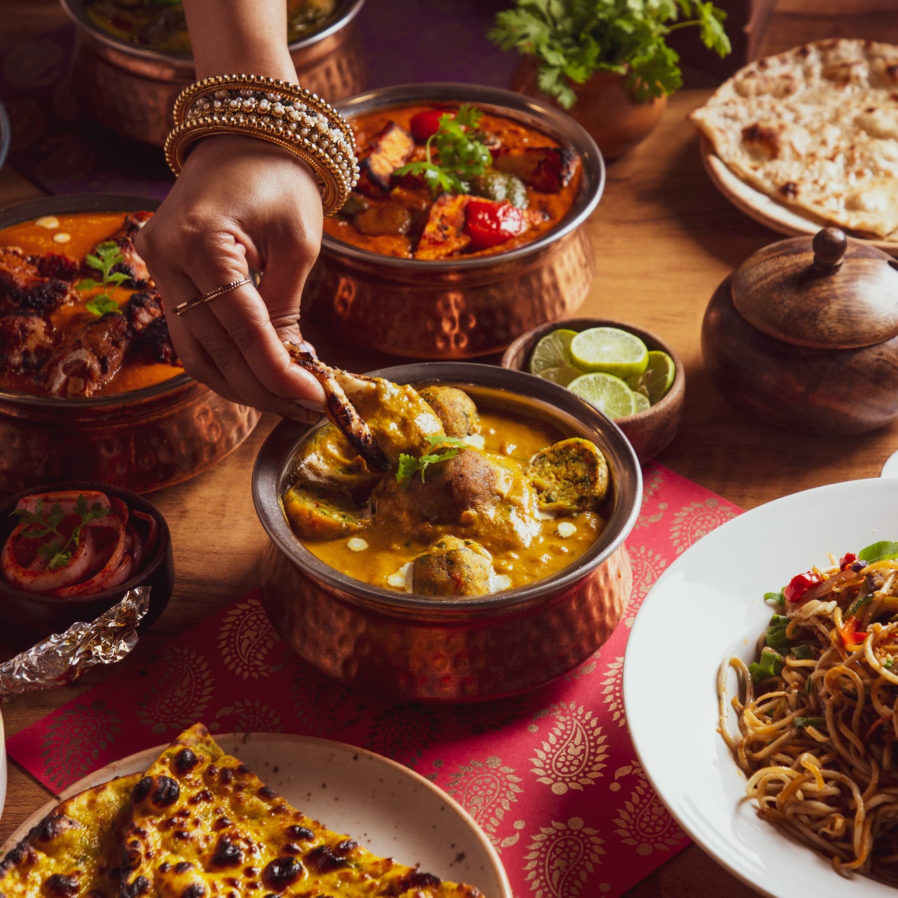 A table of curries, rice and breads being served